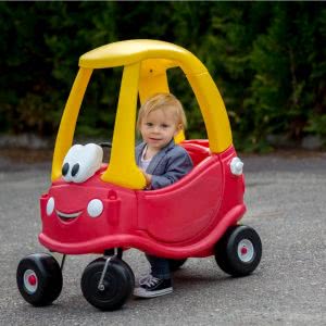 This is an image of a little boy driving a ride on toy car