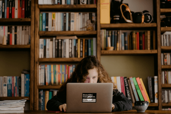 This is an image of girl sitting at a table on her laptop